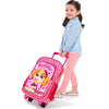 A young child is smiling and pulling a Paw Patrol Skye Deluxe Travel Trolley Backpack from Kiddies World. The child is wearing a light blue shirt, pink polka dot pants, and silver shoes. The backpack features adjustable padded shoulder straps, side mesh pockets, a puppy character with the phrase "So Cute!" and the name "Skye" on it.