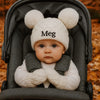 Baby in a stroller wearing a white knit hat with 'Meg' embroidered on it.