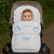 Baby in a stroller with a white cover featuring blue bows and the name 'Charlie'.