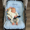 Baby sleeping in a stroller with a blue stroller liner with the name 'Harry' personalised on it.